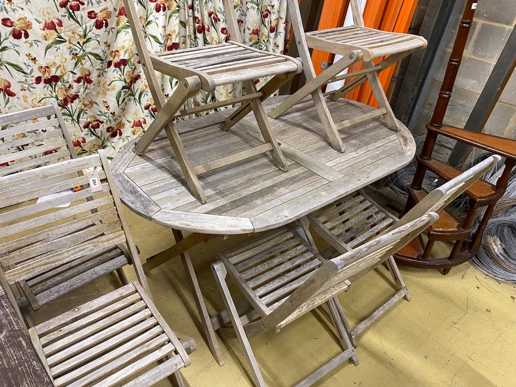 A weathered teak folding garden table, length 152cm, width 90cm, height 75cm and six teak folding garden chairs